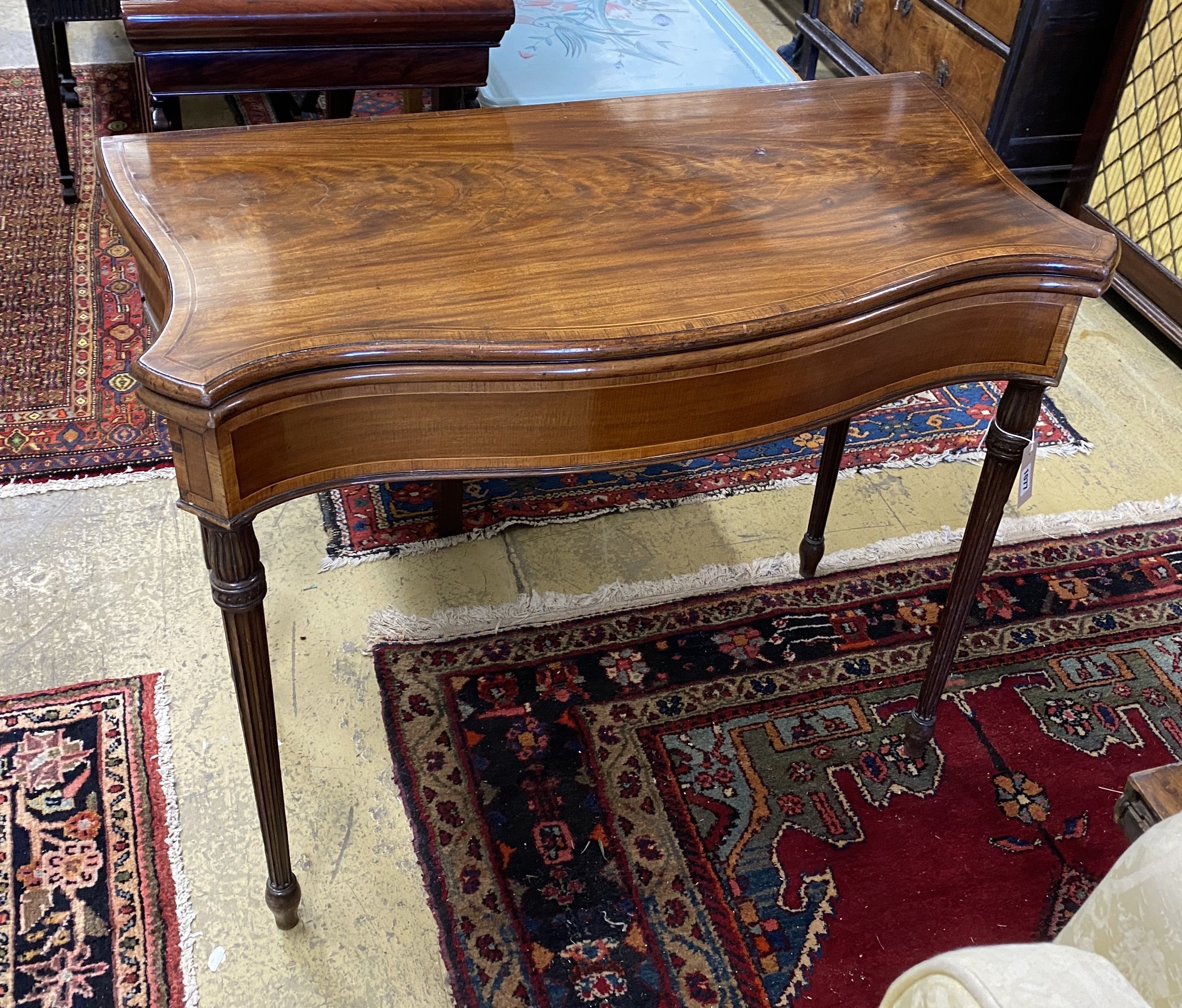A George III serpentine fronted banded mahogany folding card table, width 88cm, depth 44cm, height 74cm